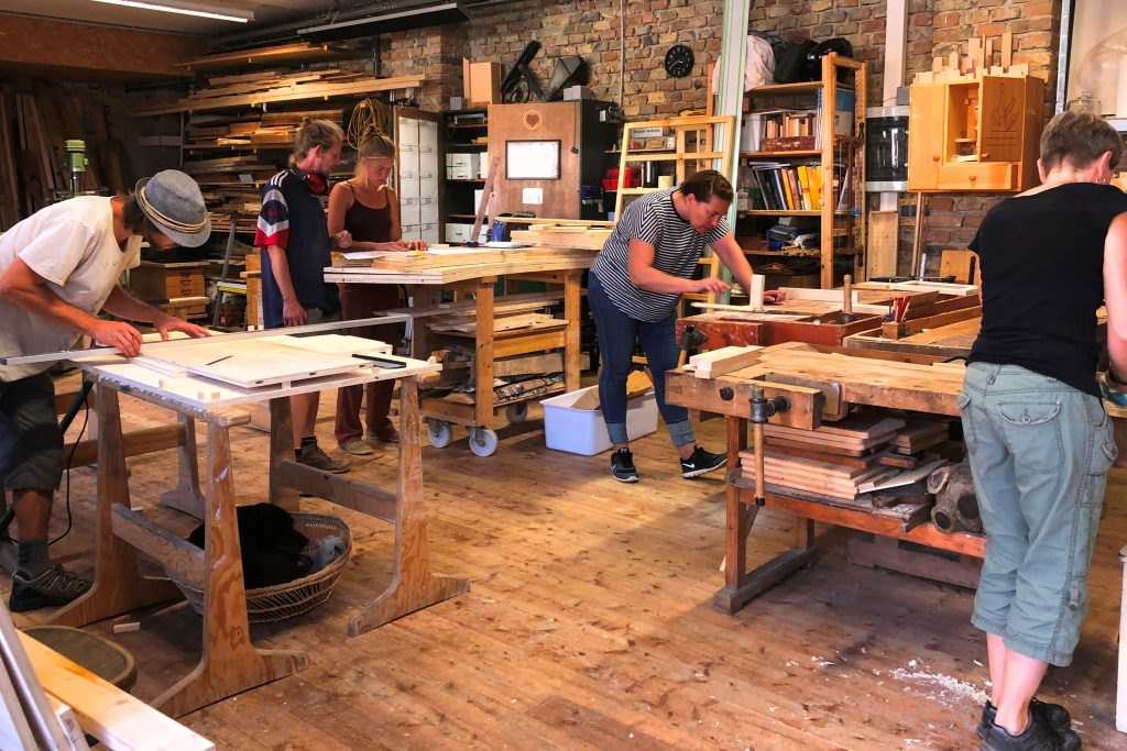 Personen setzen ihre individuellen Werkstücke im Holzatelier um